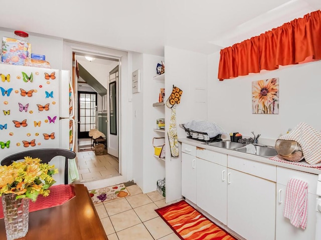 kitchen with white cabinetry, sink, white fridge, and light tile patterned floors