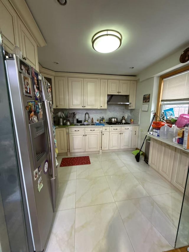 kitchen with stainless steel fridge, sink, backsplash, and cream cabinets