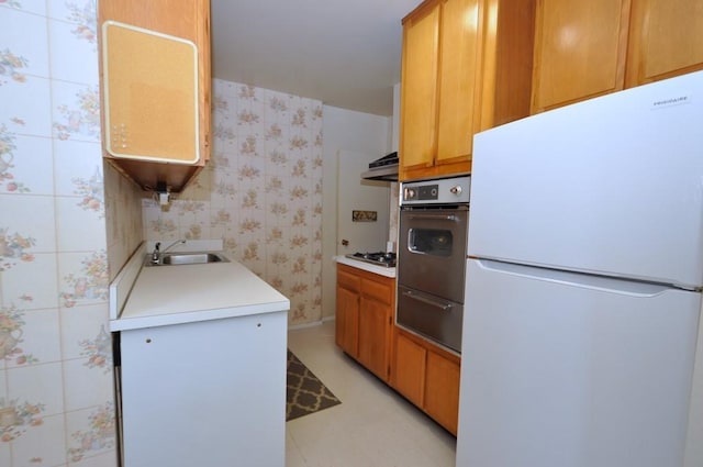 kitchen with sink, range hood, white refrigerator, wall oven, and stainless steel gas cooktop