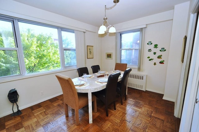 dining space with dark parquet flooring, radiator, a wealth of natural light, and an inviting chandelier