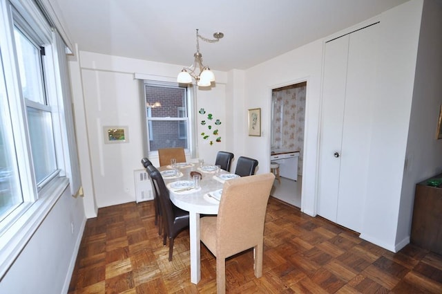 dining space featuring dark parquet flooring and a chandelier