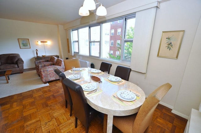 dining space featuring dark parquet flooring and an inviting chandelier