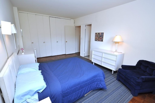 bedroom with dark parquet floors and a closet