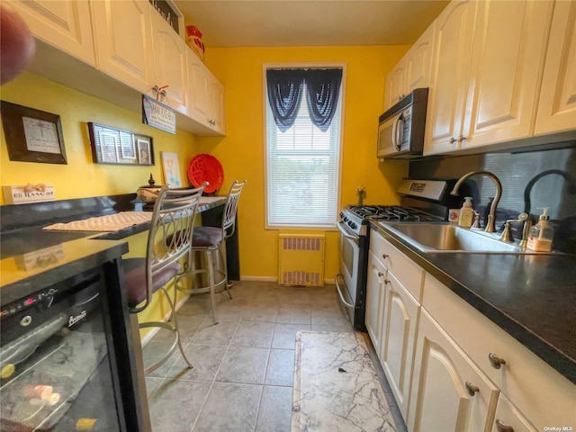 kitchen featuring light tile patterned flooring, radiator heating unit, sink, and black appliances