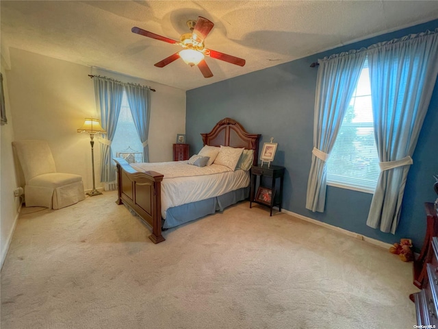 carpeted bedroom with ceiling fan and a textured ceiling