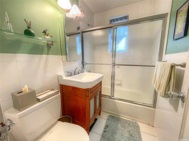 full bathroom featuring combined bath / shower with glass door, tile patterned floors, toilet, vanity, and tile walls