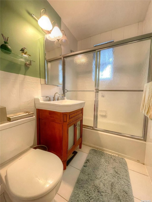 full bathroom with tile patterned floors, vanity, tile walls, enclosed tub / shower combo, and toilet