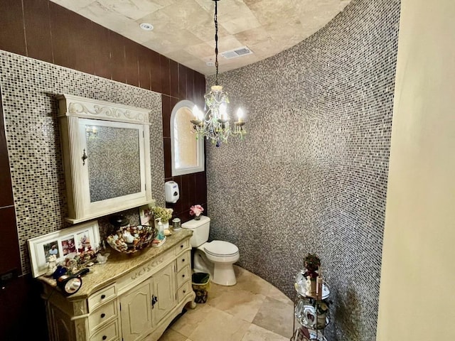 6 Hidden Pond, Muttontown, NY 11545 - bathroom with a chandelier, vanity, toilet, tile walls, and tile patterned floors