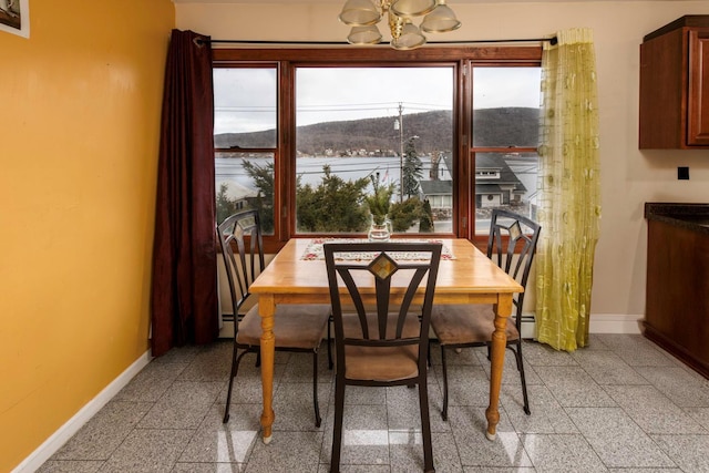 dining area featuring a chandelier, a mountain view, baseboard heating, and a wealth of natural light