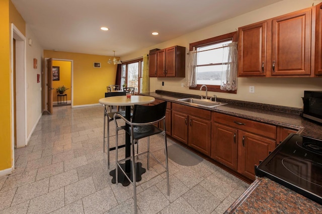 kitchen featuring sink, a notable chandelier, black / electric stove, pendant lighting, and a kitchen bar