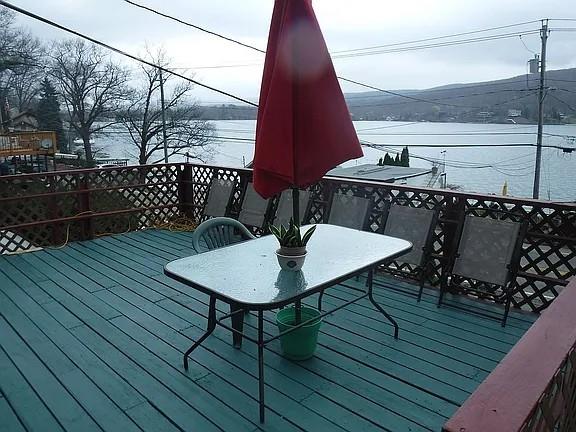 wooden deck with outdoor dining area and a water view