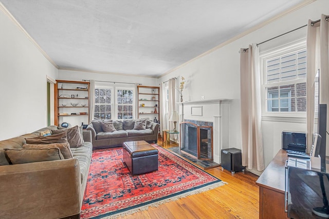 living room with crown molding, a premium fireplace, and wood finished floors