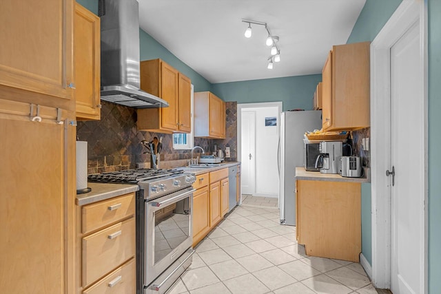 kitchen with sink, stainless steel appliances, wall chimney range hood, decorative backsplash, and light tile patterned floors