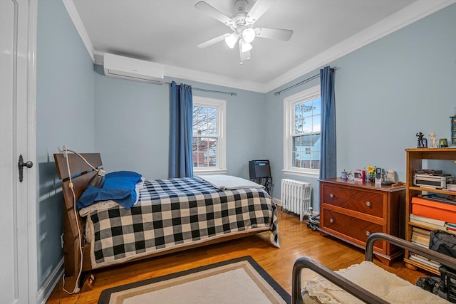 bedroom with radiator, an AC wall unit, crown molding, ceiling fan, and light hardwood / wood-style floors