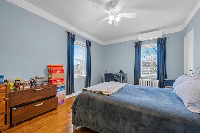 bedroom with ornamental molding, a wall unit AC, ceiling fan, radiator heating unit, and light hardwood / wood-style floors