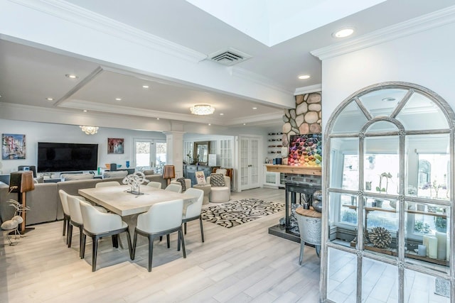 dining space featuring ornate columns, light hardwood / wood-style floors, and crown molding