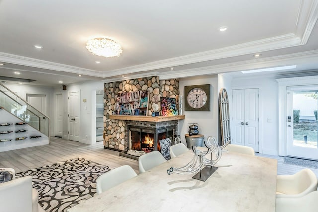 living room featuring light hardwood / wood-style flooring, crown molding, and a stone fireplace