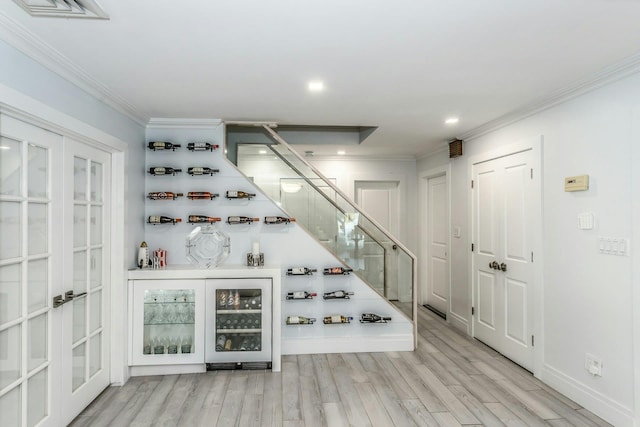 wine area featuring crown molding, beverage cooler, and light hardwood / wood-style flooring