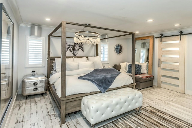 bedroom with ornamental molding, light wood-type flooring, a barn door, and a notable chandelier