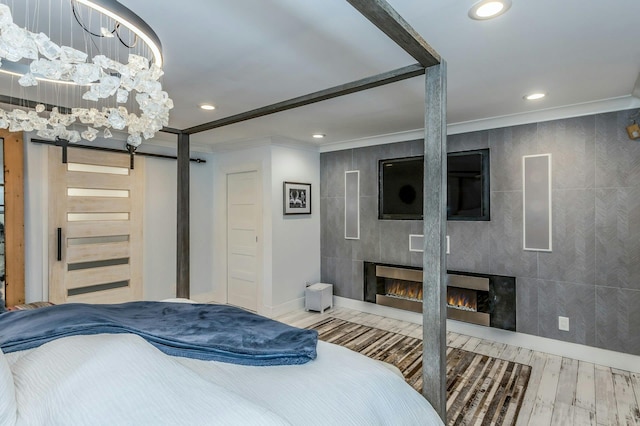 bedroom with a fireplace, ornamental molding, hardwood / wood-style flooring, and a notable chandelier