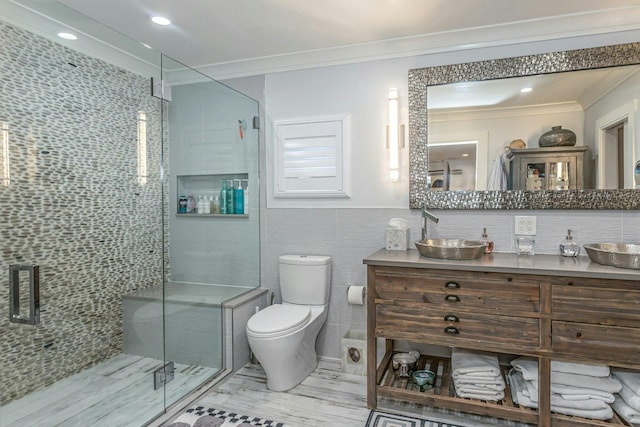 bathroom featuring tile walls, a shower with door, crown molding, and vanity