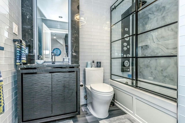 full bathroom featuring toilet, bath / shower combo with glass door, and vanity