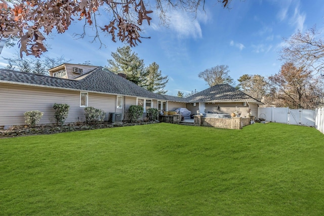 rear view of property featuring a lawn and central AC unit