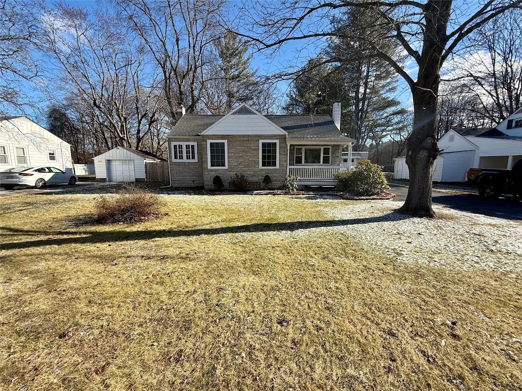 view of front of property featuring a porch, a garage, an outdoor structure, and a front yard