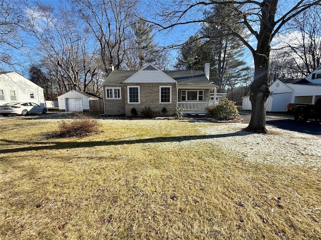 view of front of property featuring a porch, a garage, an outdoor structure, and a front yard