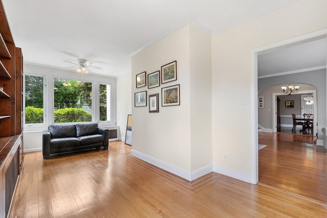 sitting room featuring light wood-type flooring, ornamental molding, and ceiling fan with notable chandelier