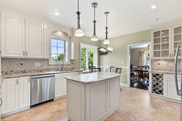 kitchen featuring dishwasher, pendant lighting, sink, white cabinets, and light stone counters