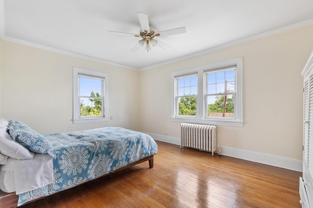 bedroom featuring ceiling fan, radiator, wood-type flooring, and crown molding