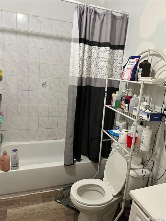 bathroom featuring shower / bath combo with shower curtain, toilet, and wood-type flooring