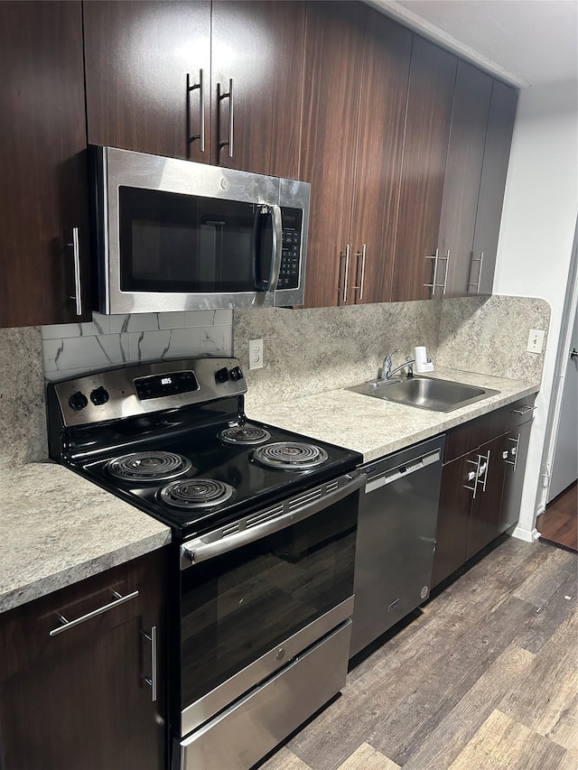 kitchen with backsplash, sink, light hardwood / wood-style flooring, appliances with stainless steel finishes, and dark brown cabinets