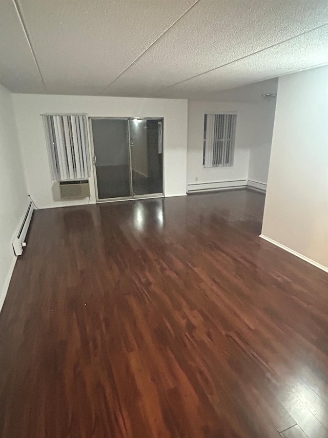 spare room featuring dark wood-type flooring, baseboard heating, and a textured ceiling