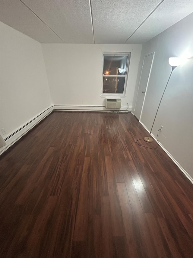 unfurnished room featuring baseboard heating, a textured ceiling, dark hardwood / wood-style flooring, and a wall mounted AC