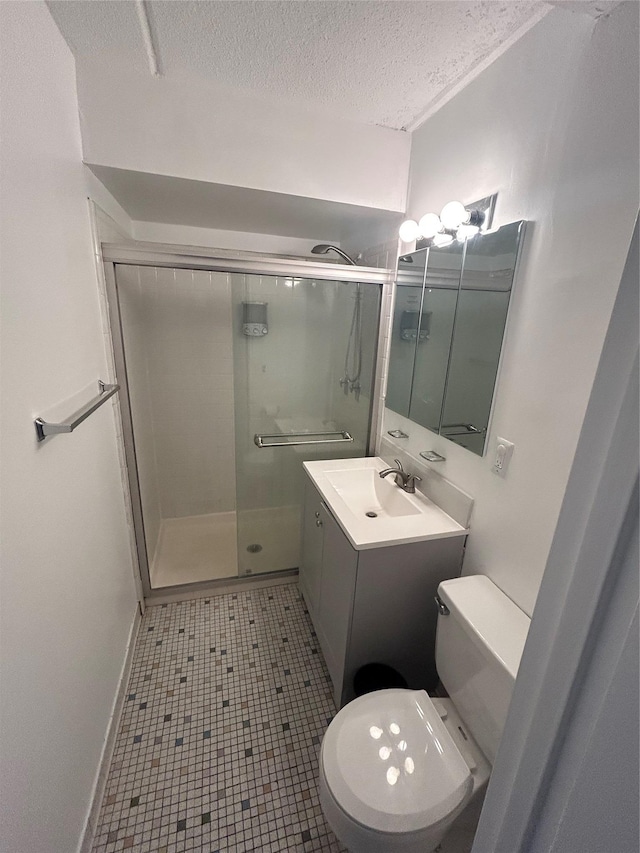 bathroom with toilet, vanity, tile patterned floors, a shower with shower door, and a textured ceiling