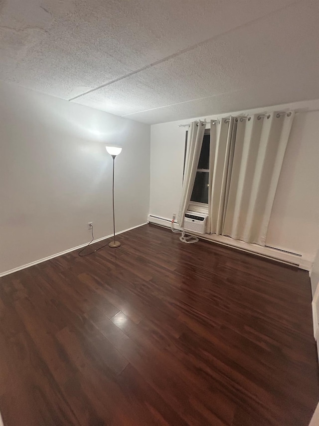 empty room with dark wood-type flooring, a textured ceiling, and a baseboard radiator