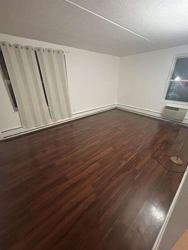 spare room with dark wood-type flooring, a textured ceiling, and a wall mounted air conditioner