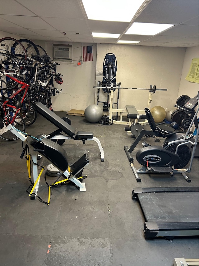 exercise room featuring a drop ceiling and an AC wall unit