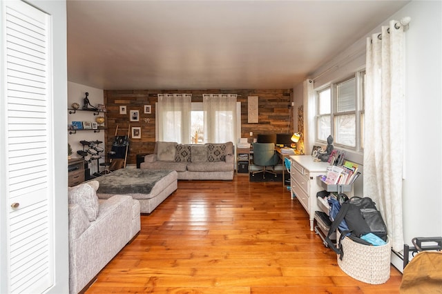 living room featuring light wood-type flooring, a baseboard heating unit, and wood walls