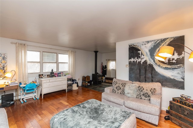 living room featuring a baseboard heating unit, a healthy amount of sunlight, a wood stove, and hardwood / wood-style floors