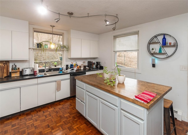 kitchen with white cabinetry, butcher block countertops, a center island, dishwasher, and sink