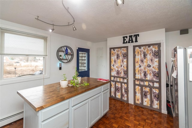 kitchen featuring a baseboard radiator, a textured ceiling, a kitchen island, butcher block counters, and stainless steel fridge