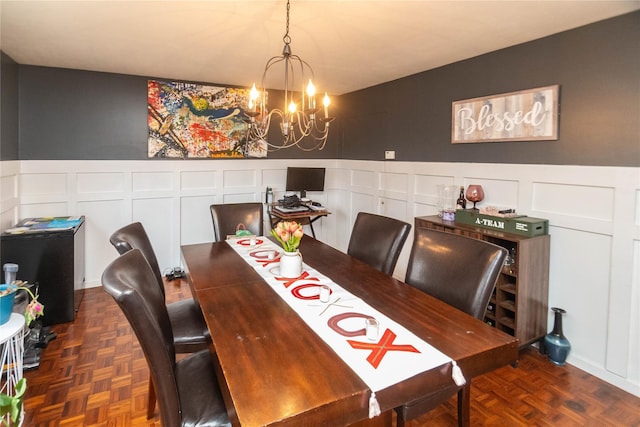 dining area featuring dark parquet flooring and a chandelier