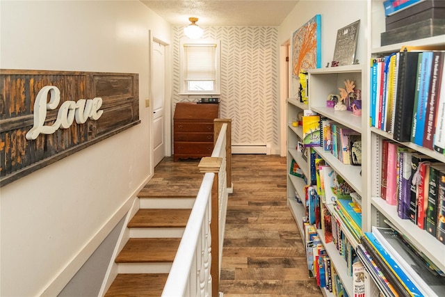 hall with baseboard heating, dark hardwood / wood-style floors, and a textured ceiling