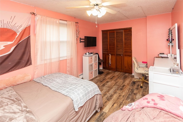 bedroom featuring ceiling fan, a closet, dark hardwood / wood-style flooring, and baseboard heating