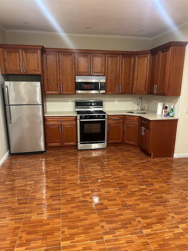 kitchen featuring wood finished floors, a sink, appliances with stainless steel finishes, backsplash, and crown molding