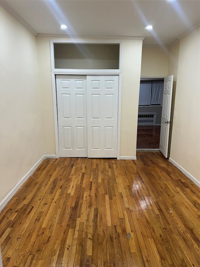 unfurnished bedroom with hardwood / wood-style flooring, recessed lighting, baseboards, ornamental molding, and a closet