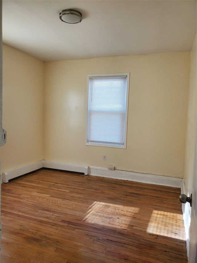 spare room with hardwood / wood-style flooring and a baseboard radiator